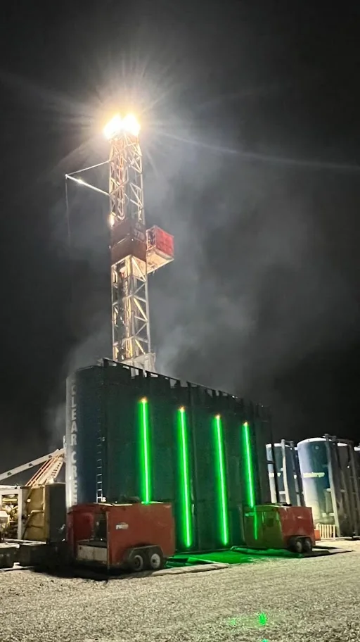A night-time industrial site with GTT SHIELD light bars glowing green on equipment, readable from ground level.